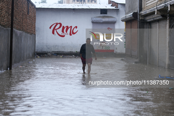 A Nepali man is wading through the flooded water in Nepal on July 6, 2024. 