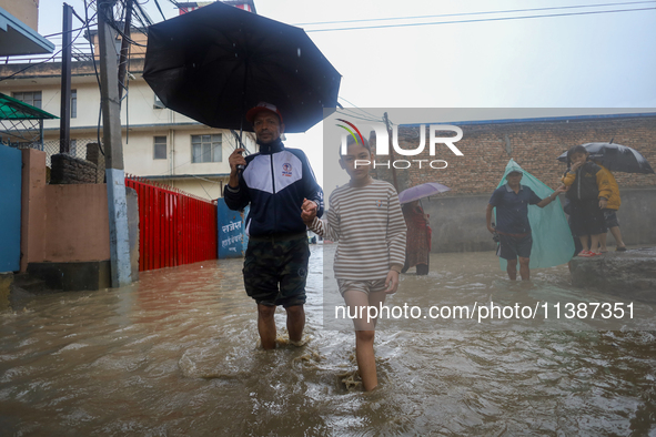 People are wading through the flood in a slum in Kathmandu, Nepal, on July 6, 2024 