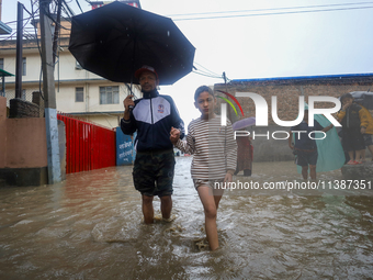 People are wading through the flood in a slum in Kathmandu, Nepal, on July 6, 2024 (