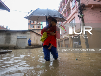 A Nepali man is carrying his child and wading through the flooded water in Kathmandu, Nepal, on July 6, 2024. (