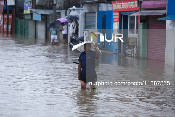 A Nepali man is wading through the flooded water in Nepal on July 6, 2024. 