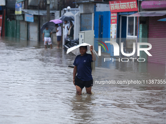 A Nepali man is wading through the flooded water in Nepal on July 6, 2024. (