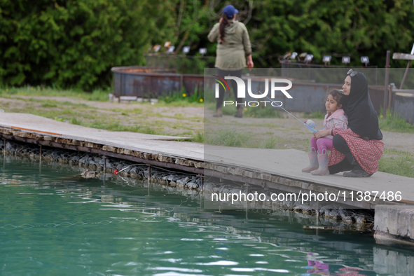 A woman and her daughter are fishing for rainbow trout at a pond in Stouffville, Ontario, Canada, on May 12, 2024. 