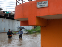 A man is helping a girl cross the flooded road in Tikathali, Kathmandu, on July 6, 2024, following incessant rainfall. (