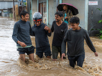 People are crossing the flooded road in Tikathali, Kathmandu, on July 06, 2024, following incessant rainfall (