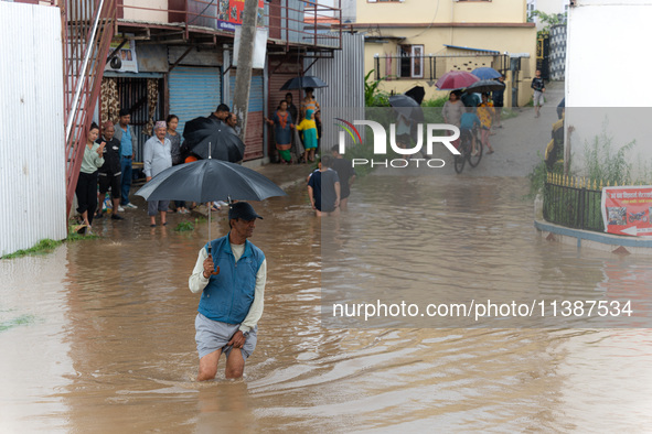 A man is crossing the flooded road in Tikathali, Kathmandu, on July 6, 2024, following incessant rainfall 