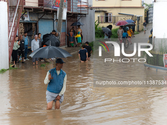 A man is crossing the flooded road in Tikathali, Kathmandu, on July 6, 2024, following incessant rainfall (