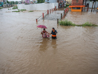 A man is helping a girl cross the flooded road in Tikathali, Kathmandu, on July 6, 2024, following incessant rainfall. (