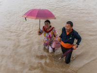 A man is helping a girl cross the flooded road in Tikathali, Kathmandu, on July 6, 2024, following incessant rainfall. (