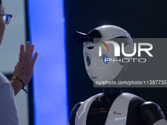 A visitor is interacting with a humanoid robot at the World Artificial Intelligence Conference at the Shanghai World Expo Exhibition Center...