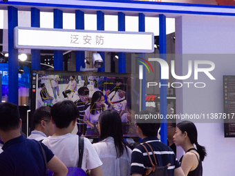 Visitors are being seen in front of a large screen of the security system at the World Artificial Intelligence Conference at the Shanghai Wo...