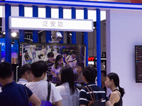 Visitors are being seen in front of a large screen of the security system at the World Artificial Intelligence Conference at the Shanghai Wo...