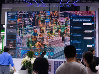 Visitors are being seen in front of a large screen of the security system at the World Artificial Intelligence Conference at the Shanghai Wo...