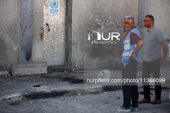 Men are working for the United Nations Relief and Works Agency (URNWA), assessing the damage at the entrance of the agency's warehouse after...