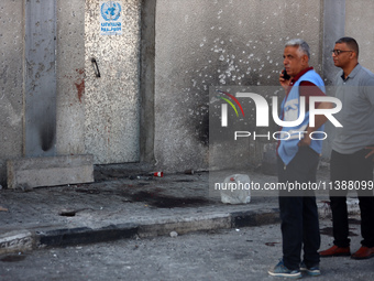 Men are working for the United Nations Relief and Works Agency (URNWA), assessing the damage at the entrance of the agency's warehouse after...