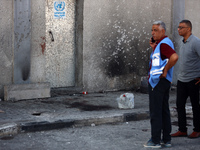 Men are working for the United Nations Relief and Works Agency (URNWA), assessing the damage at the entrance of the agency's warehouse after...