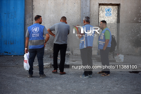 Men are working for the United Nations Relief and Works Agency (URNWA), assessing the damage at the entrance of the agency's warehouse after...