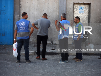 Men are working for the United Nations Relief and Works Agency (URNWA), assessing the damage at the entrance of the agency's warehouse after...