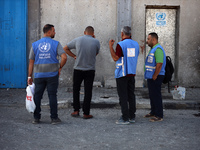 Men are working for the United Nations Relief and Works Agency (URNWA), assessing the damage at the entrance of the agency's warehouse after...