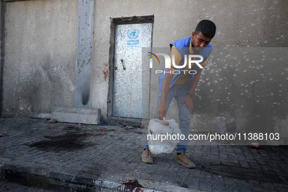 A man is working for the United Nations Relief and Works Agency (URNWA) and is removing a damaged object near the blood of a victim at the e...