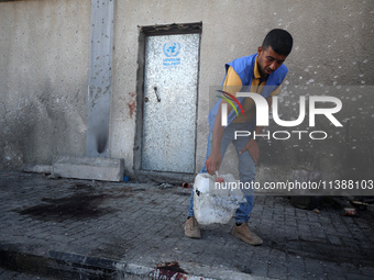 A man is working for the United Nations Relief and Works Agency (URNWA) and is removing a damaged object near the blood of a victim at the e...