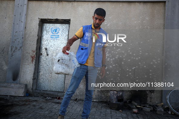 A man is working for the United Nations Relief and Works Agency (URNWA) and is removing a damaged object near the blood of a victim at the e...