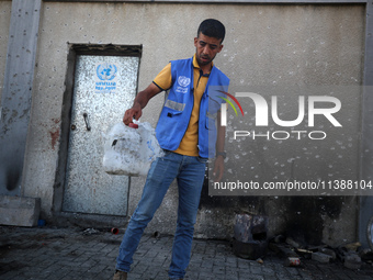 A man is working for the United Nations Relief and Works Agency (URNWA) and is removing a damaged object near the blood of a victim at the e...