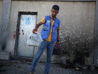 A man is working for the United Nations Relief and Works Agency (URNWA) and is removing a damaged object near the blood of a victim at the e...