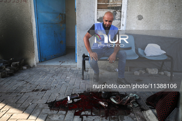 A man is working for the United Nations Relief and Works Agency (URNWA) and is staring at the blood of a victim at the entrance of the agenc...