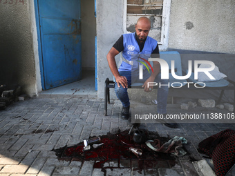 A man is working for the United Nations Relief and Works Agency (URNWA) and is staring at the blood of a victim at the entrance of the agenc...