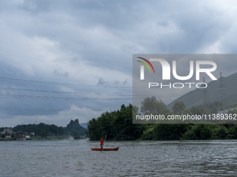 Security guards are patrolling the water as a power plant is opening a gate to release floodwater in Enshi, Hubei province, China, on July 6...