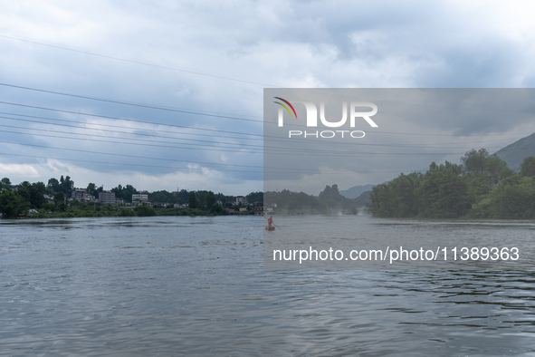 Security guards are patrolling the water as a power plant is opening a gate to release floodwater in Enshi, Hubei province, China, on July 6...