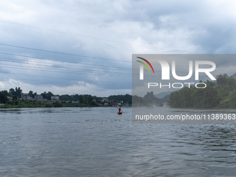 Security guards are patrolling the water as a power plant is opening a gate to release floodwater in Enshi, Hubei province, China, on July 6...