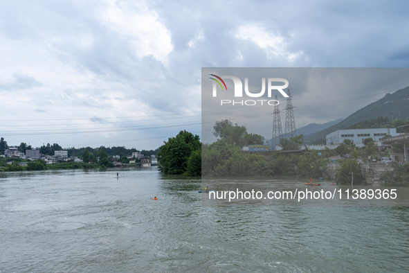 Security guards are patrolling the water as a power plant is opening a gate to release floodwater in Enshi, Hubei province, China, on July 6...