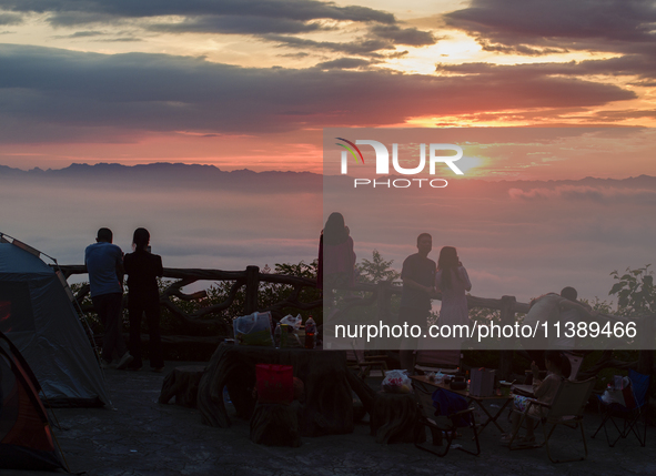 Tourists are watching the sunrise from a viewing platform over the Three Gorges in Yichang, China, on July 7, 2024. 