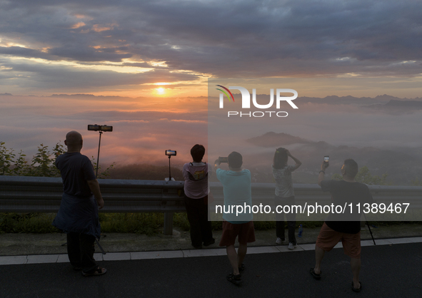 Tourists are watching the sunrise from a viewing platform over the Three Gorges in Yichang, China, on July 7, 2024. 