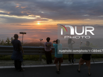 Tourists are watching the sunrise from a viewing platform over the Three Gorges in Yichang, China, on July 7, 2024. (