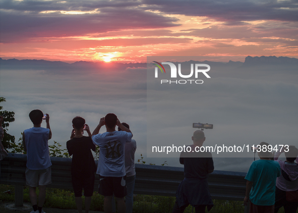 Tourists are watching the sunrise from a viewing platform over the Three Gorges in Yichang, China, on July 7, 2024. 