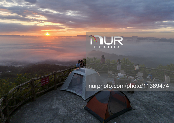 Tourists are watching the sunrise from a viewing platform over the Three Gorges in Yichang, China, on July 7, 2024. 