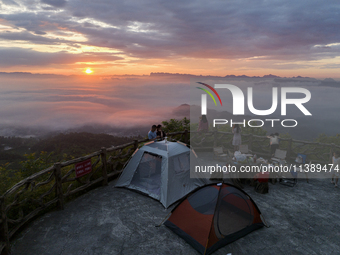 Tourists are watching the sunrise from a viewing platform over the Three Gorges in Yichang, China, on July 7, 2024. (