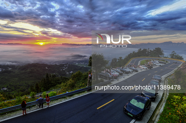 Tourists are watching the sunrise from a viewing platform over the Three Gorges in Yichang, China, on July 7, 2024. 