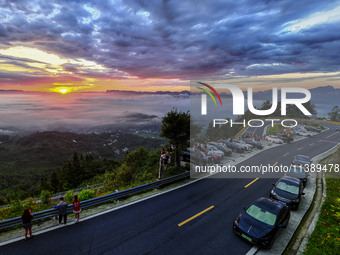 Tourists are watching the sunrise from a viewing platform over the Three Gorges in Yichang, China, on July 7, 2024. (