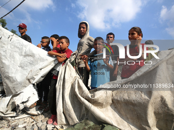 Palestinians are assessing the damage following an Israeli strike in Al-Zawayda in the central Gaza Strip on July 7, 2024, amid the ongoing...