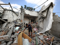 A Palestinian boy is checking the rubble of a residential building destroyed in an Israeli strike in Al-Zawayda in the central Gaza Strip on...