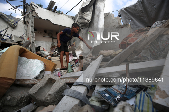 A Palestinian boy is checking the rubble of a residential building destroyed in an Israeli strike in Al-Zawayda in the central Gaza Strip on...