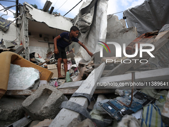 A Palestinian boy is checking the rubble of a residential building destroyed in an Israeli strike in Al-Zawayda in the central Gaza Strip on...