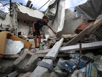 A Palestinian boy is checking the rubble of a residential building destroyed in an Israeli strike in Al-Zawayda in the central Gaza Strip on...