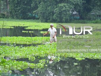 A man is walking through a flooded road after heavy rainfall in Nagaon District of Assam, India, on July 7, 2024. (