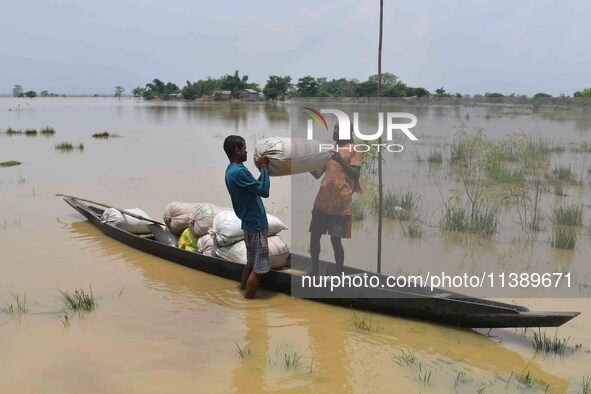 Villagers are shifting liquefied sacks of rice to a safer place in Nagaon District of Assam, India, on July 7, 2024. 