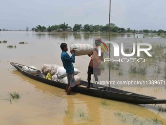 Villagers are shifting liquefied sacks of rice to a safer place in Nagaon District of Assam, India, on July 7, 2024. (